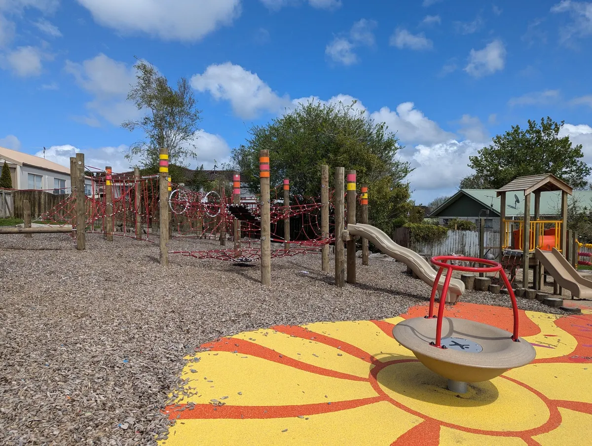 Red rope climbing nets, slide and spinner on a sunflower rubber surface at Devonshire Reserve playground