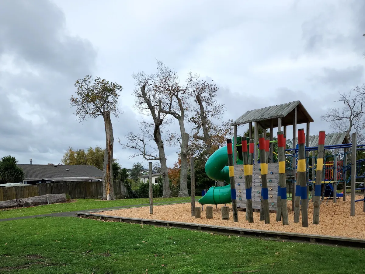Spiral slide, climbing wall and rainbow log climbers at Blundell Park playground, Howick