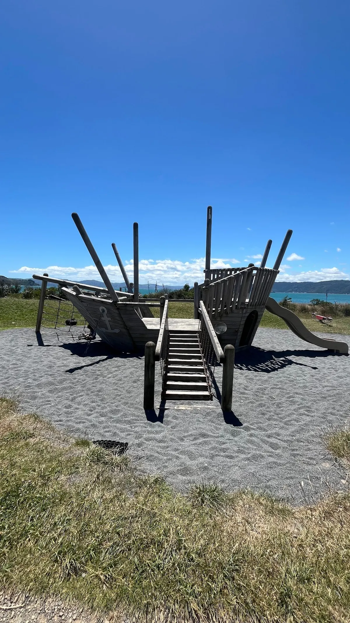Wooden pirate ship play structure with slide beside the harbour at Churchill Park playground, Seatoun
