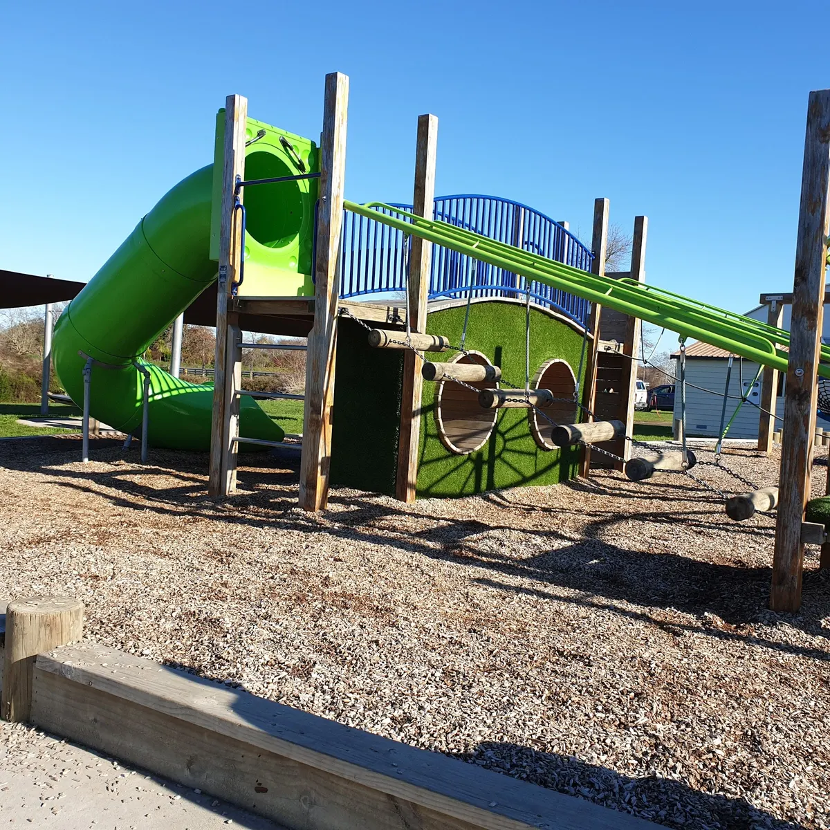 Green tube slide and rope bridge play structure at Childrens Playground & Biketrack, Cambridge