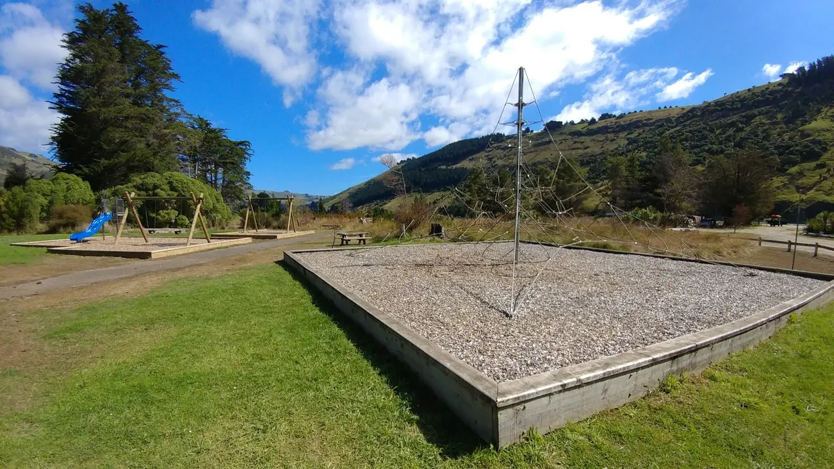 Rope net climbing pyramid and swings in the playground at Okains Bay campground, Banks Peninsula