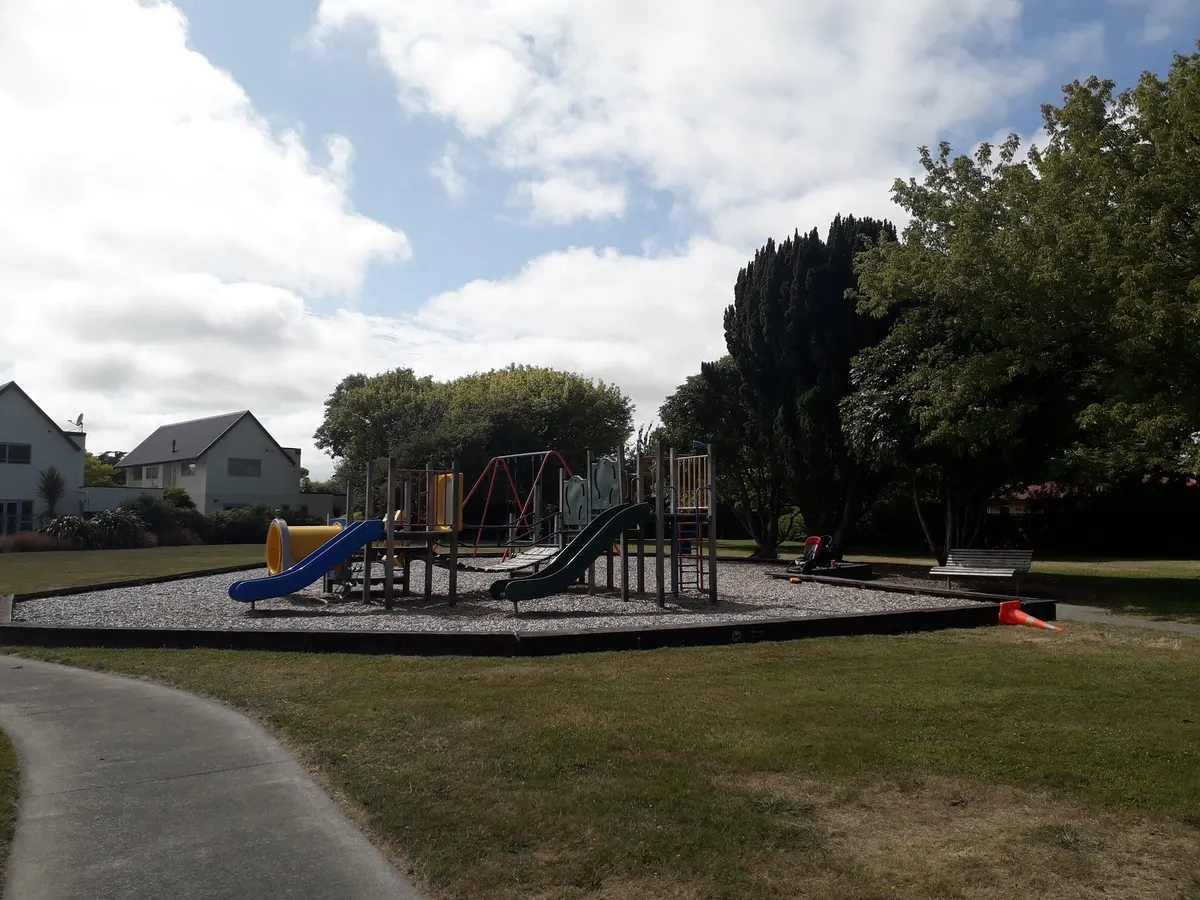 Multi-play structure with blue and green slides on a bark pad at Champion Reserve playground, Edgeware