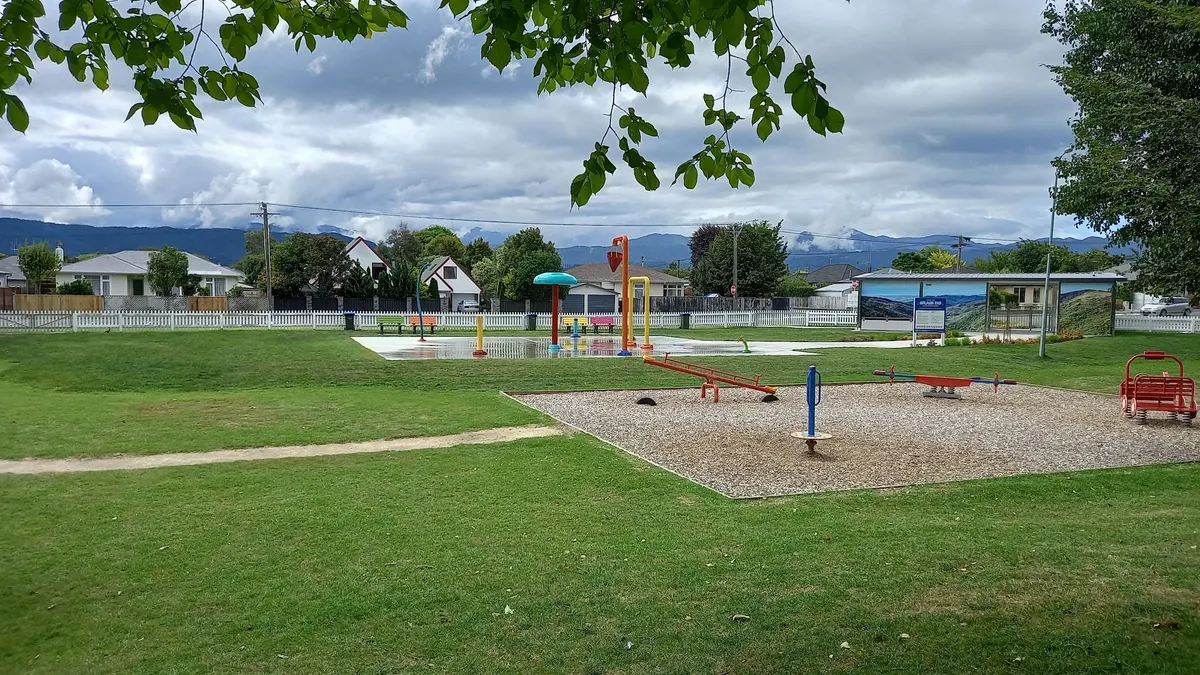 Splash pad jets and seesaws on bark beside the lawn at Jubilee Park playground, Levin
