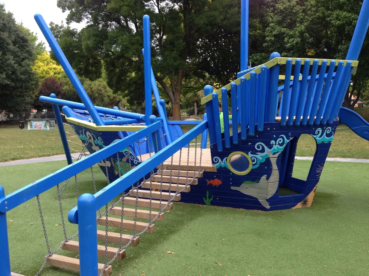 Blue pirate ship climbing structure with rope bridge at Lions Community Park playground, Mayfair