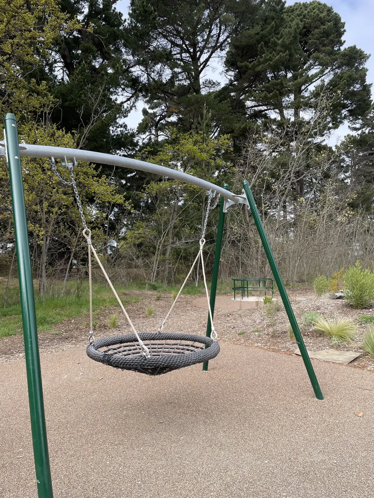 Nest swing on soft surfacing among trees at Woodland Playground, Rawhiti Domain, New Brighton
