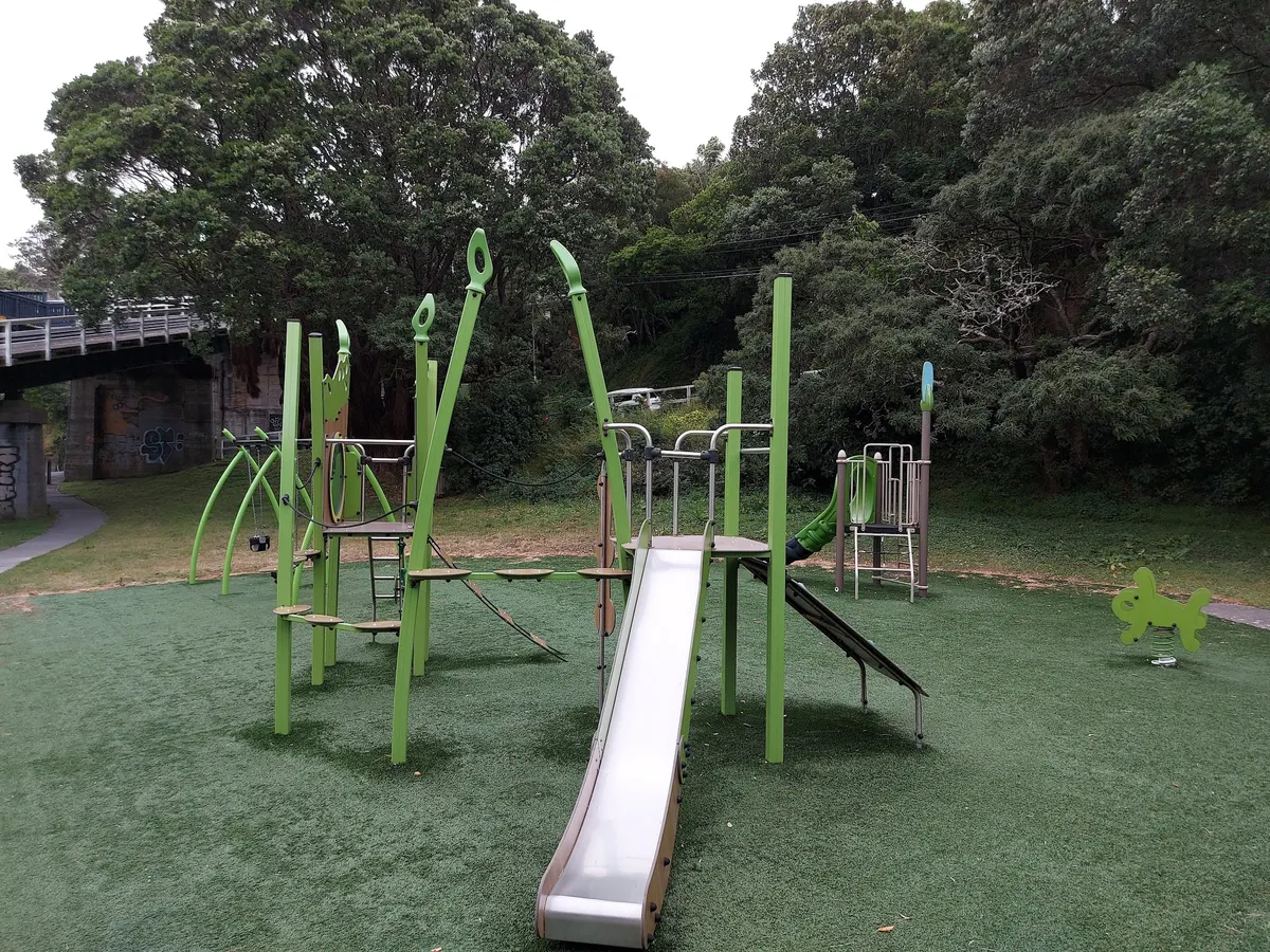 Metal slide and green climbing frame on artificial turf at Salamanca Road playground, Kelburn