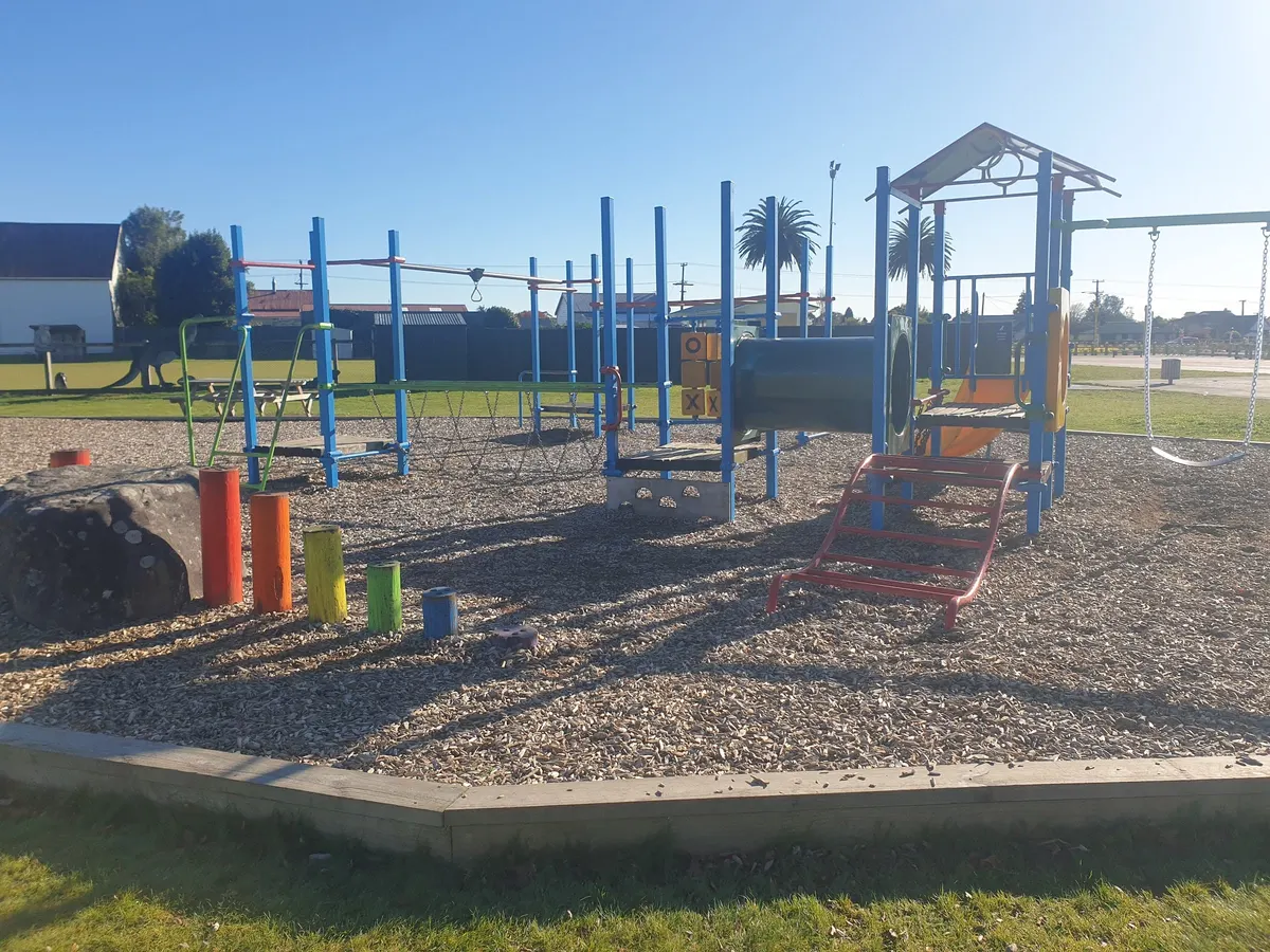 Blue climbing frames and wooden fort on wood chip at Victoria Park playground, Stratford