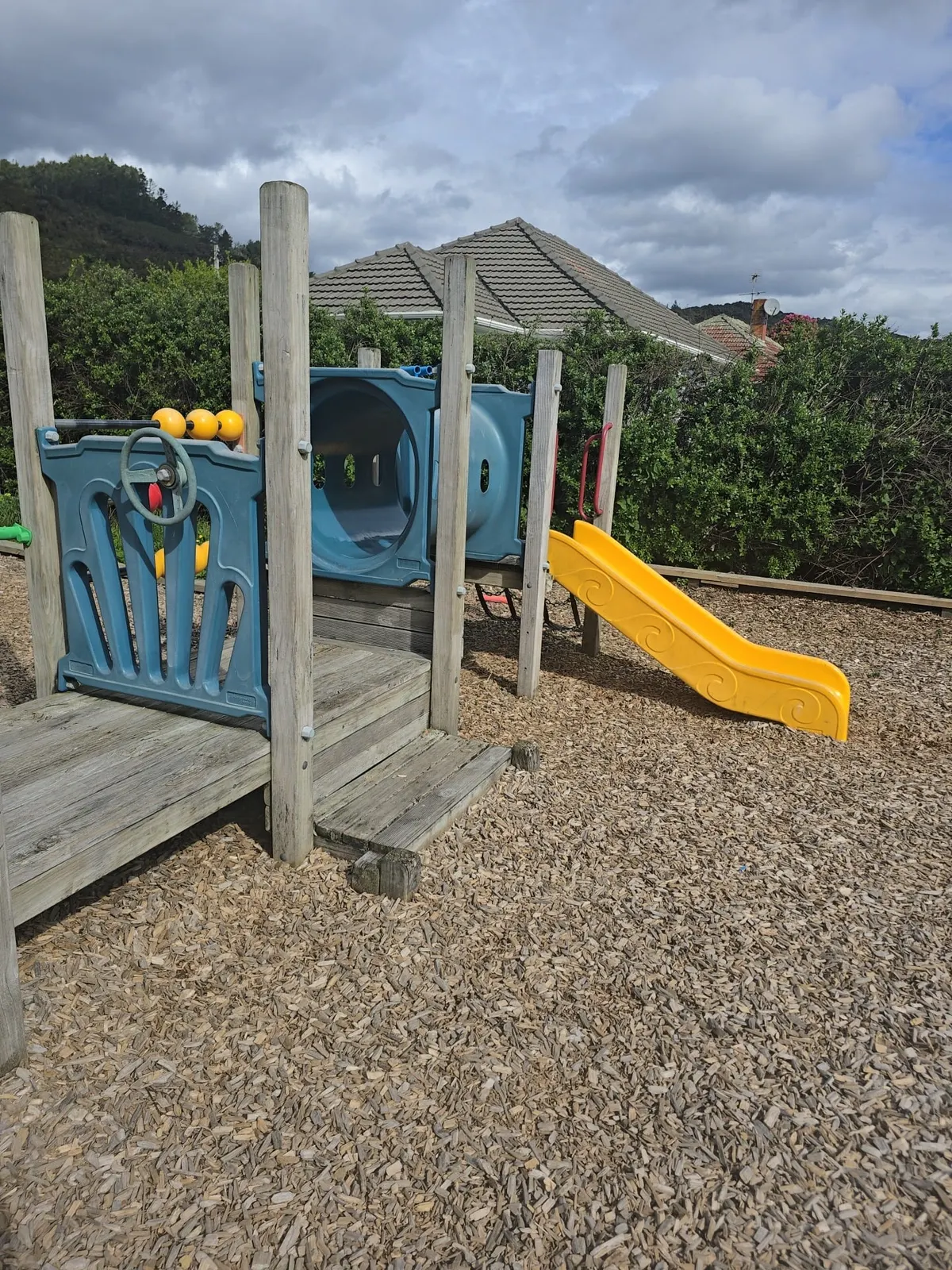 Wooden play structure with blue panels and a yellow slide at Taita Park playground, Lower Hutt