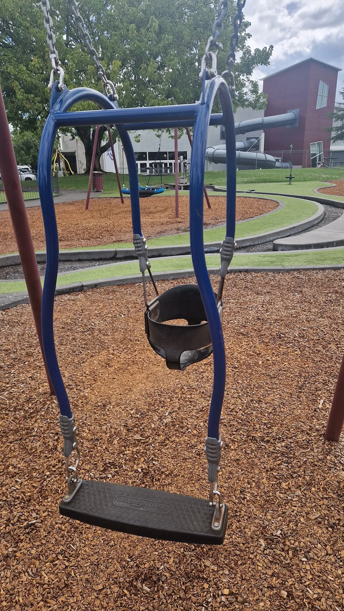 Basket swing and flat seat swing over bark chip at Our Space playground, Te Awamutu Rose Garden