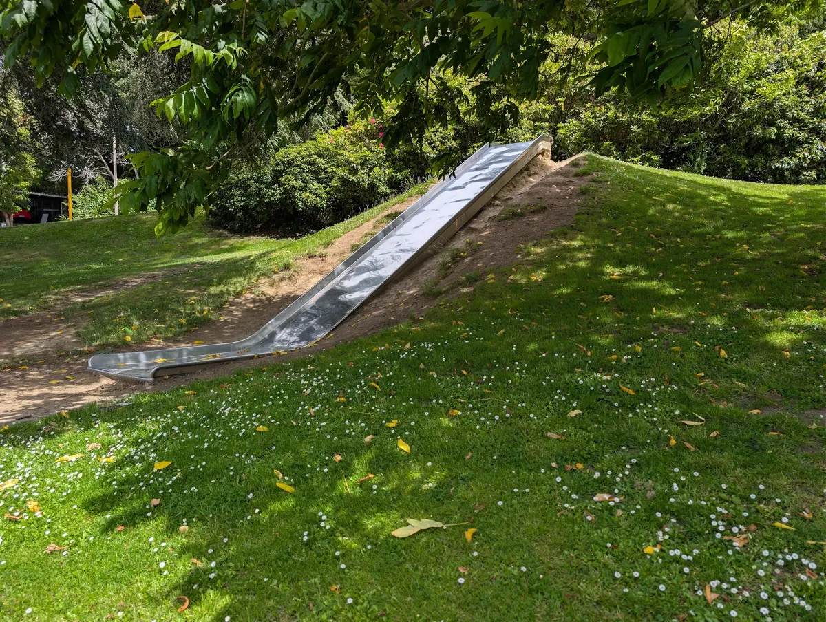 Long metal slide running down a grassy bank at Arthur Street Playground, central Dunedin