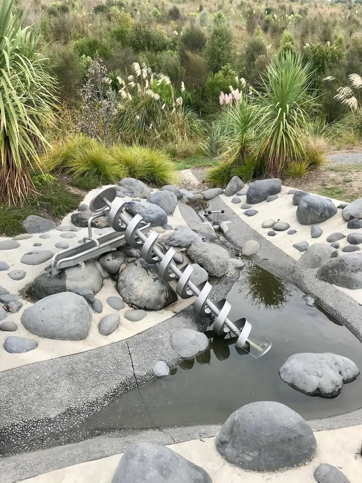 Archimedes screw lifting water from a rock-lined pool at The Lakes Waterpark, Pyes Pa, Tauranga