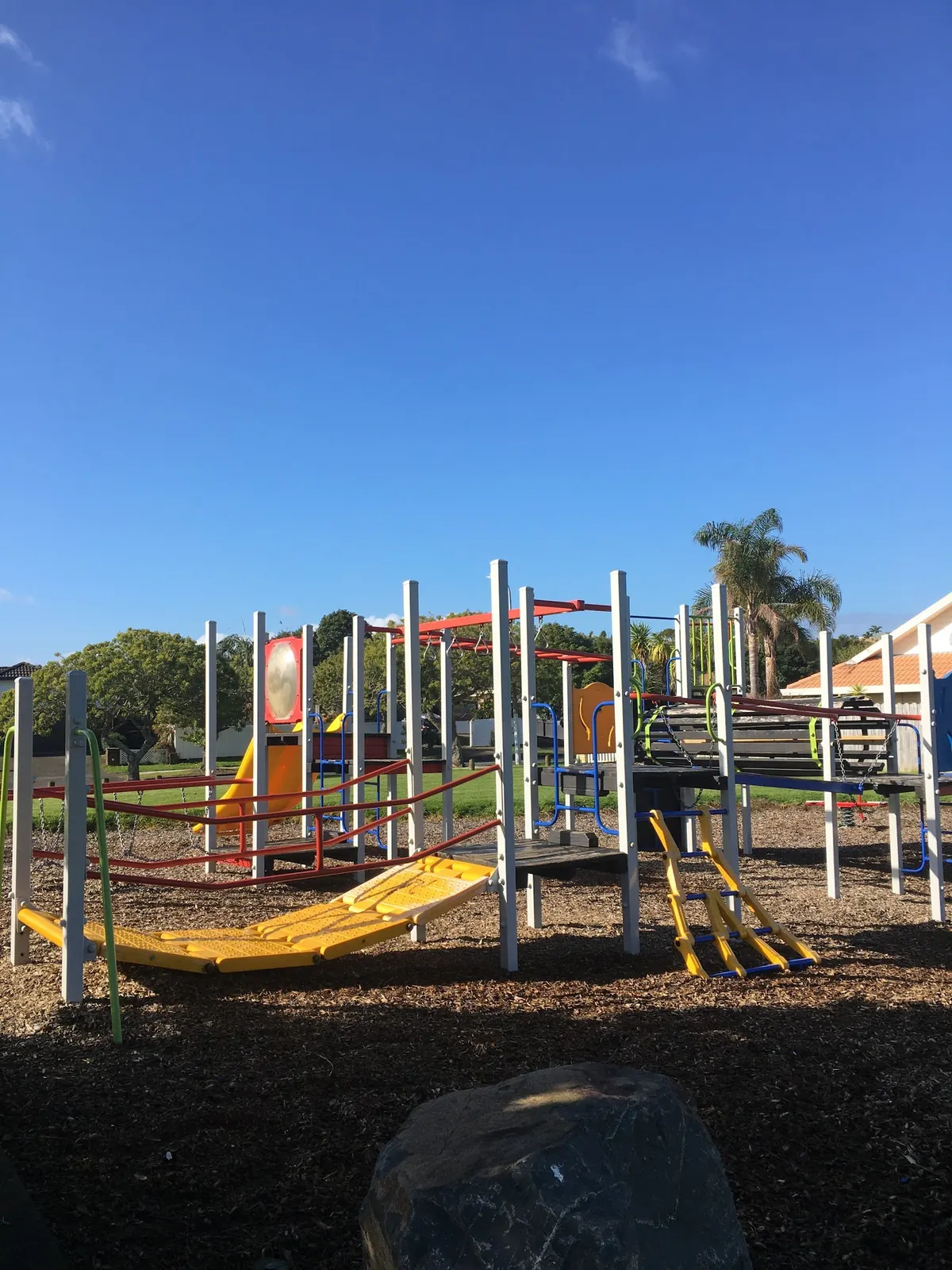 Climbing frame with slide and yellow bridge on bark at Kilimanjaro Park playground, Northpark