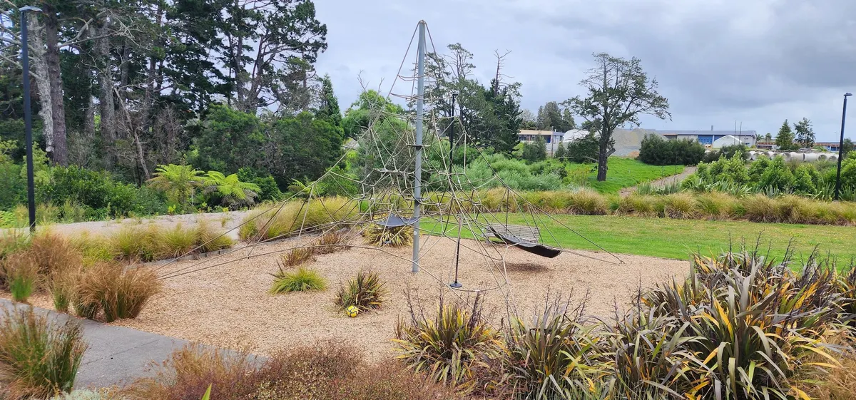 Rope climbing pyramid and swing on wood chip at Rosedale Park playground, Auckland