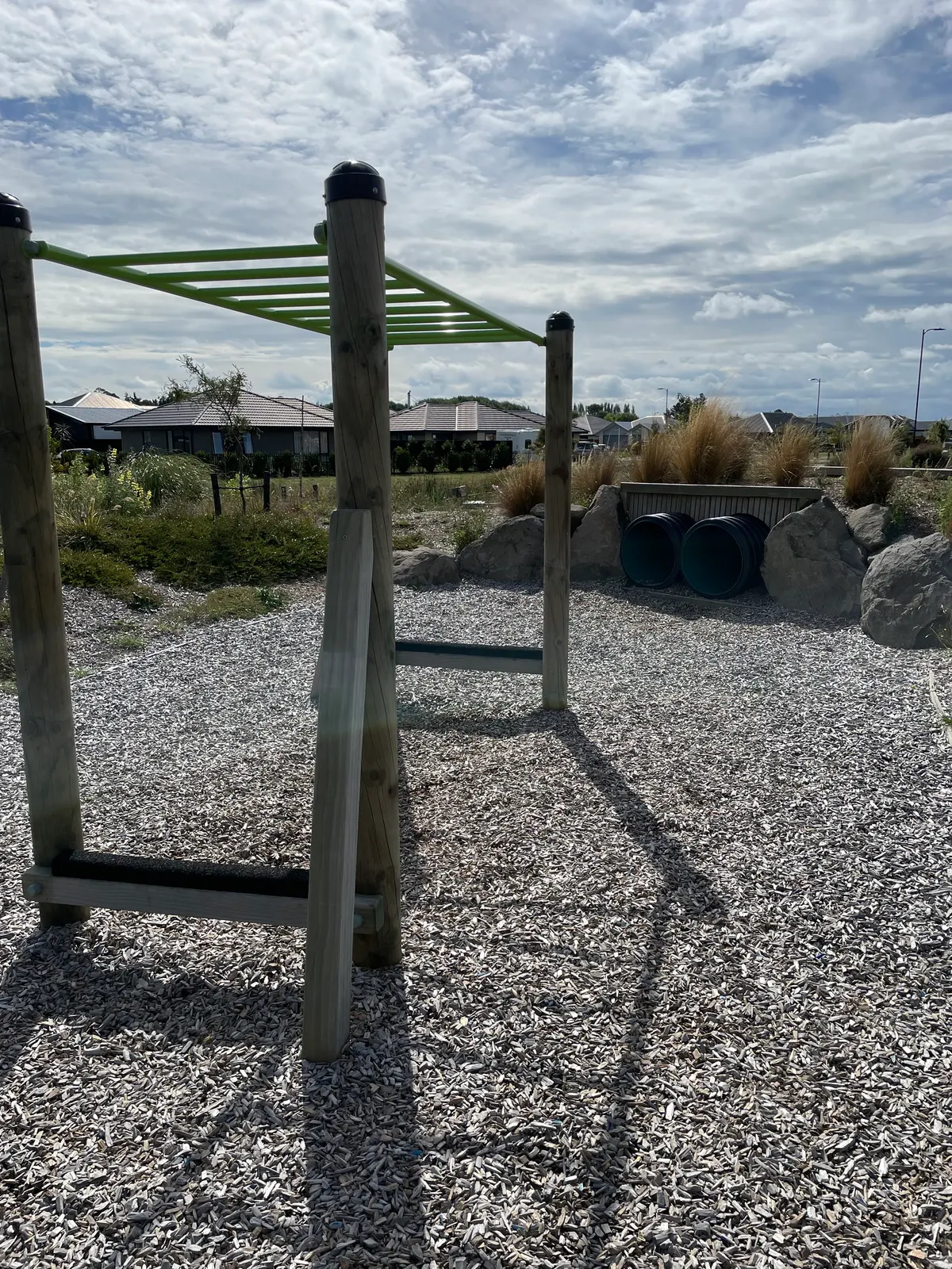Overhead ladder and black tunnel pipes on a bark play area at Aviemore Park Playground, Prestons