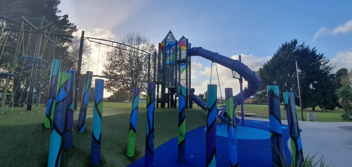 Painted posts and a tall tube slide on the climbing tower at Dominion Park playground, Nawton