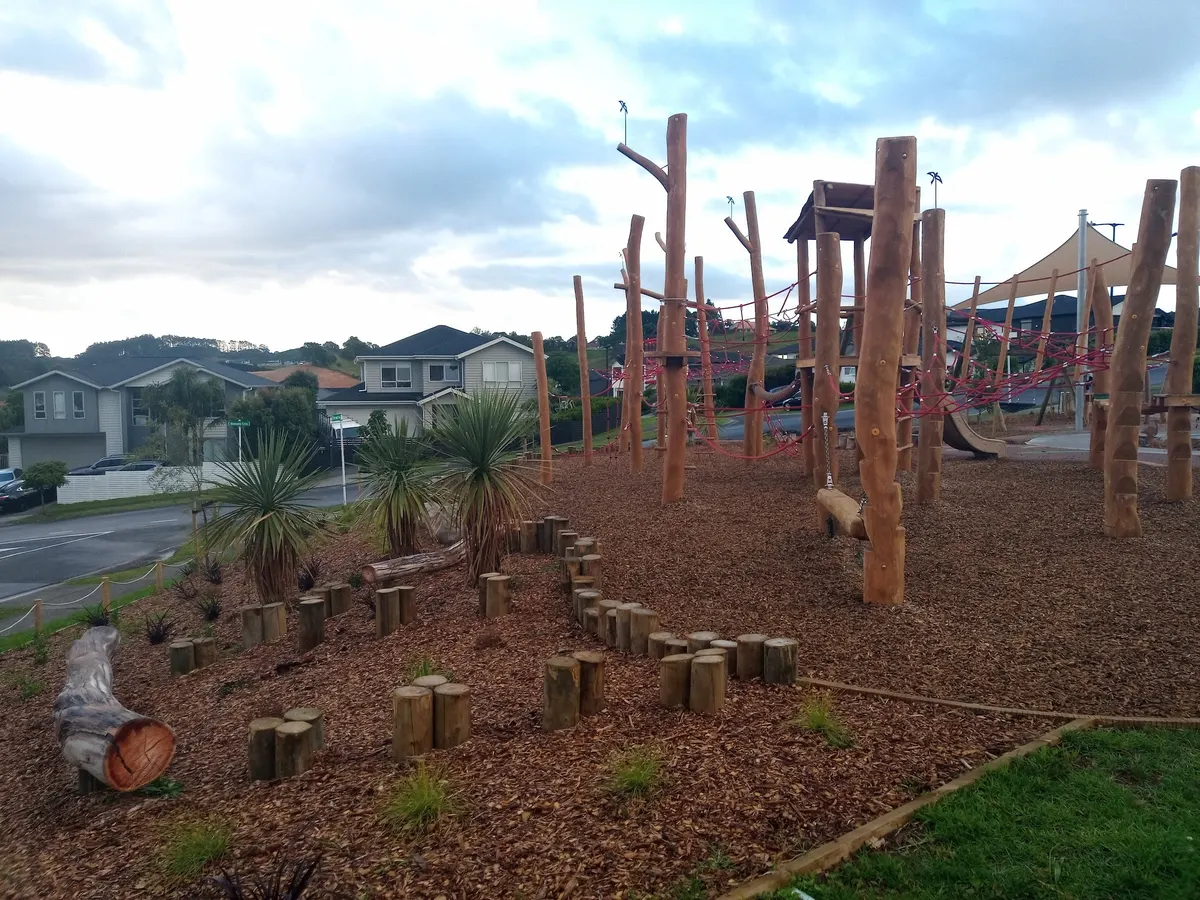 Tall timber poles and rope climbing course on bark at 86 Harvest Ave playground, Orewa