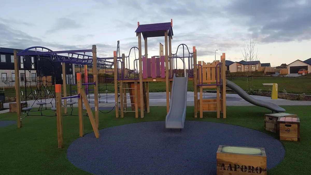 Multi-play tower with slides and climbing net on artificial grass at Te Inuwai Park playground, Glenview