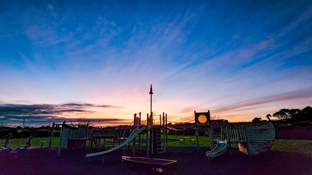 Wooden ship play structure with slides at dusk, Celaeno Park Playground, Kelvin Grove