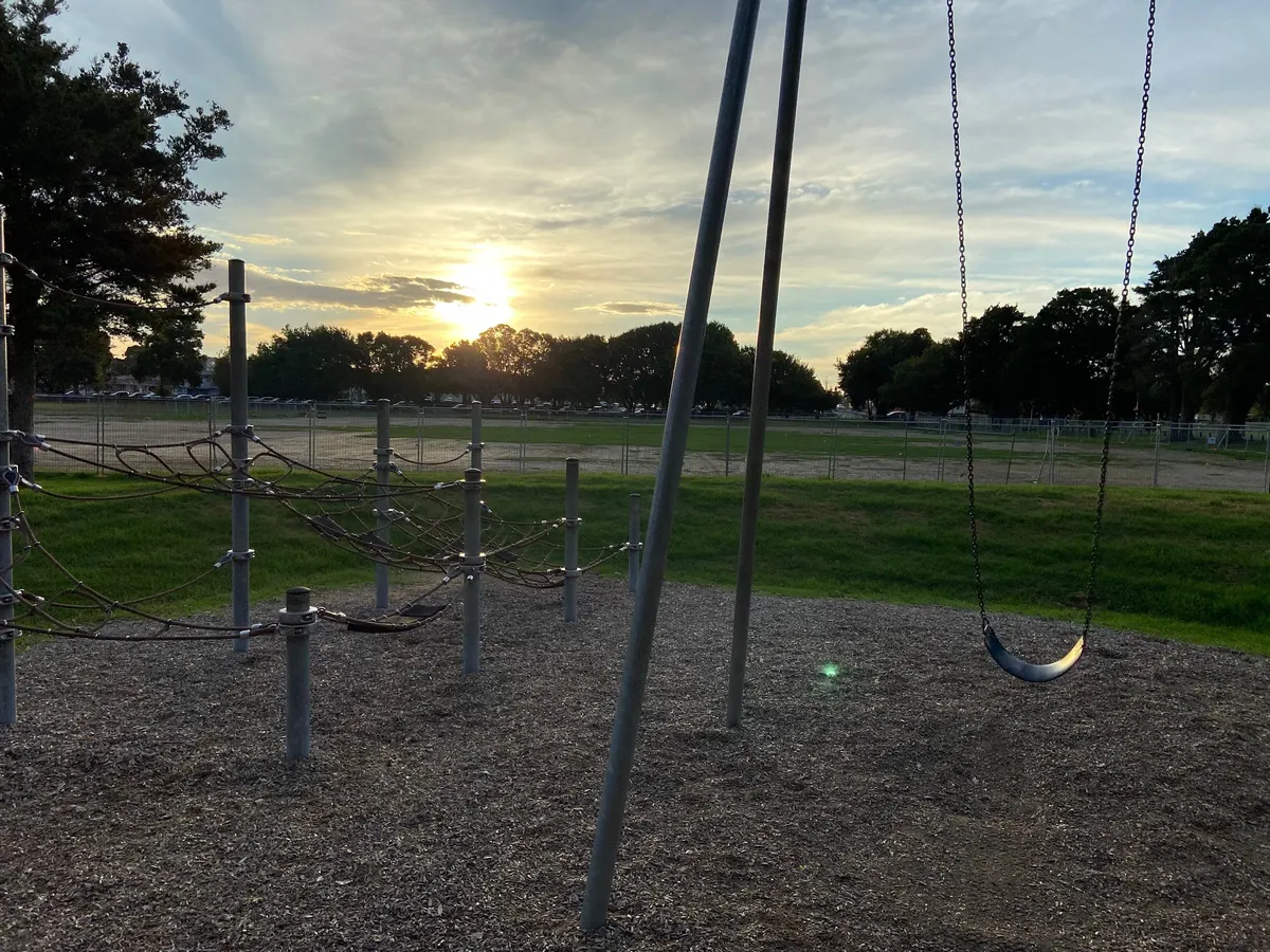 Rope climbing frame and swing on bark at Bledisloe Park playground, Pukekohe, at sunset