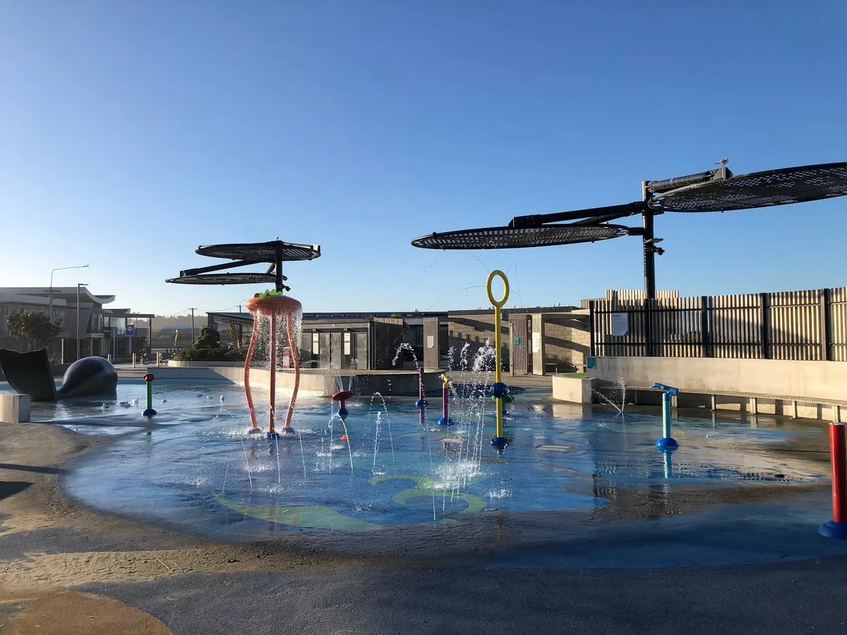 Whale splash pad with water jets and sun shades beside the sea at New Brighton Beachside Playground