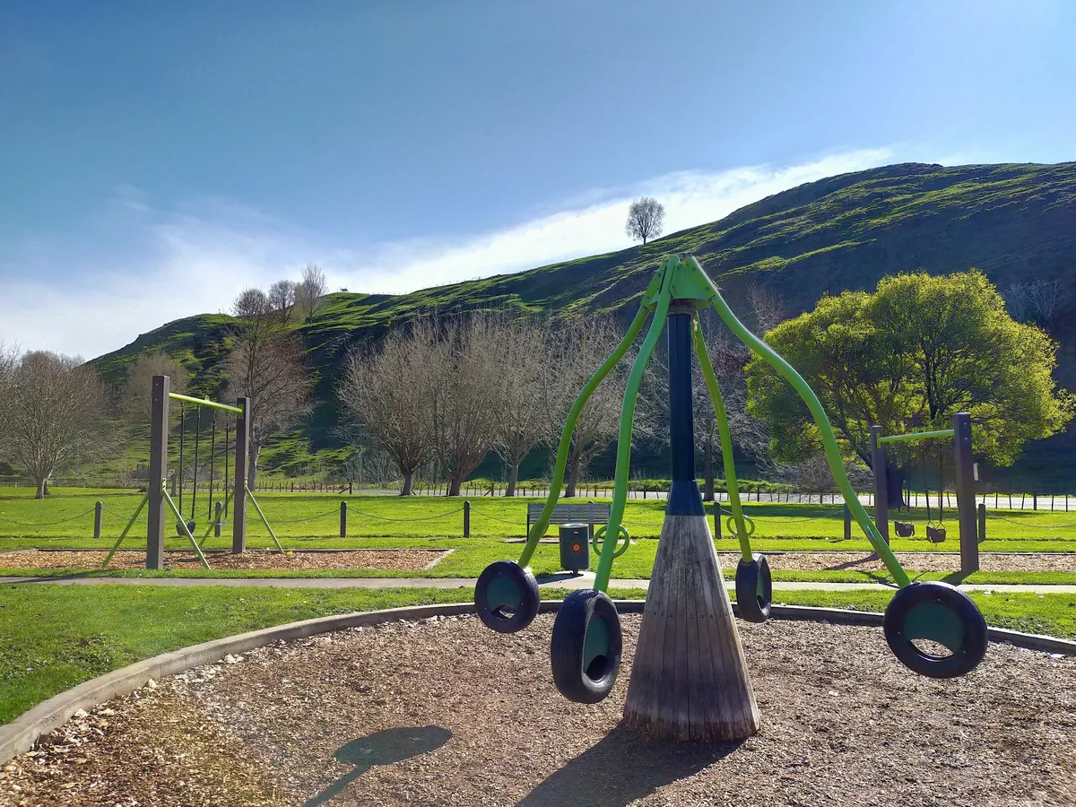 Rocktopus tyre spinner with a green hill behind at Puketapu Park playground, Hawke's Bay