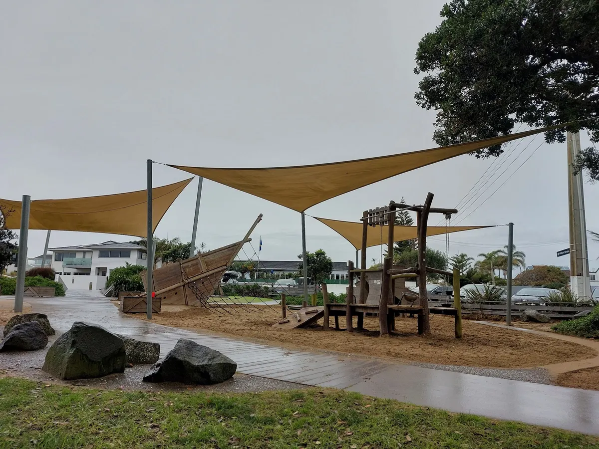 Timber ship climber and shade sails over sand at Milford Reserve Playground, Milford