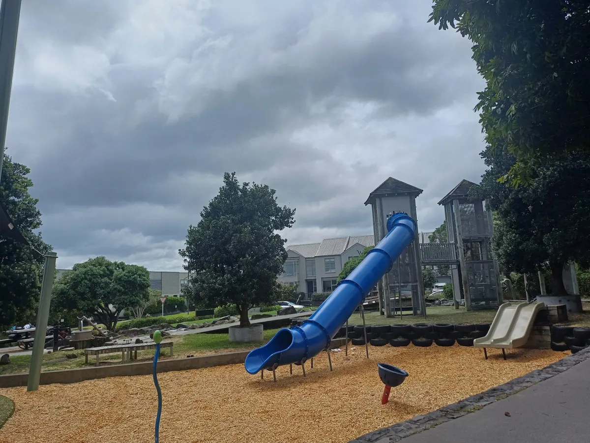 Blue tube slide and mesh towers on bark at Playtime Park playground, Mount Wellington