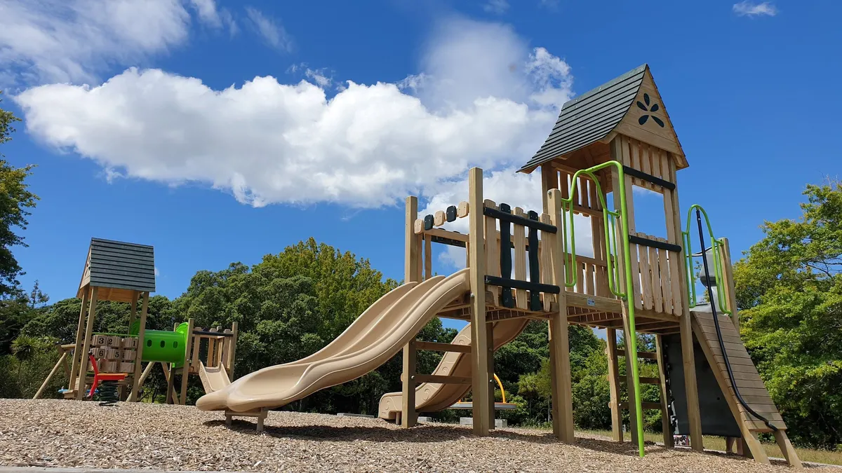 Timber play tower with beige slides on bark at La Rosa Garden Reserve playground, Green Bay