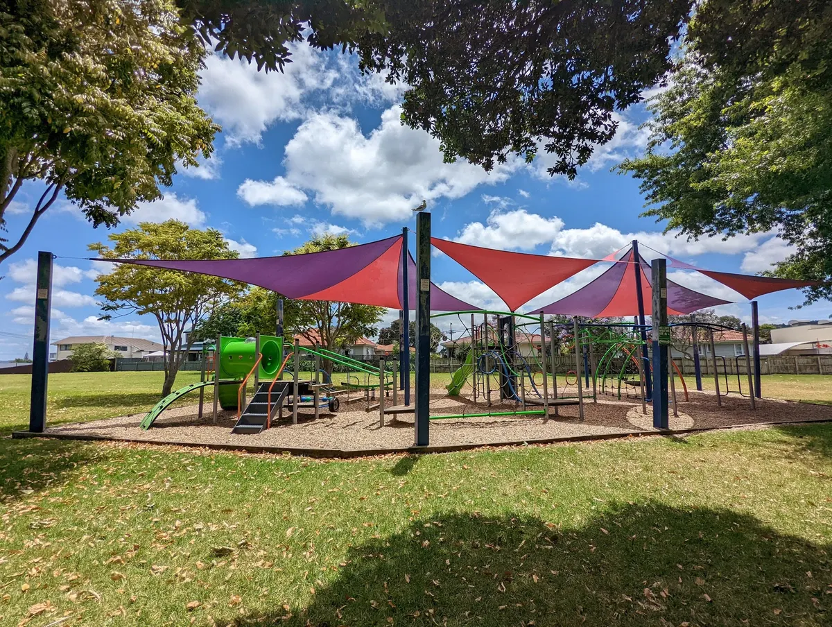 Play structures under red and purple shade sails at Sherwood Park playground, Onerahi