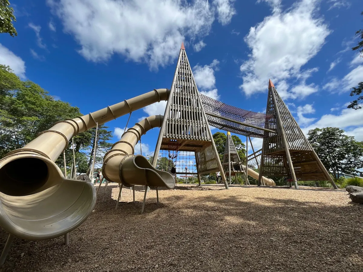 Wooden pyramid towers with long tunnel slides and rope net bridge at Tui Glen playground, Henderson