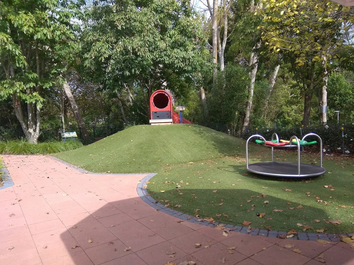 Grassy mound with tunnel slide and roundabout at Hamilton Gardens Destination Playground