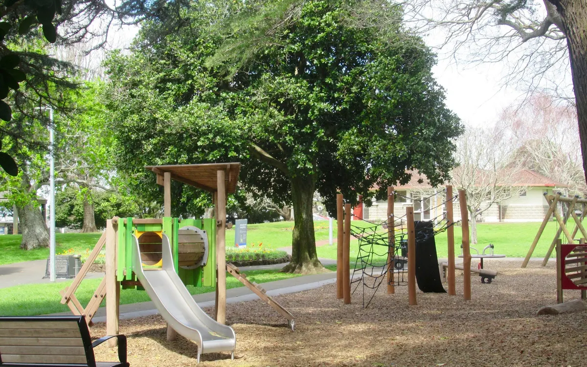 Timber tunnel and junior slide with net climber under big trees at Outhwaite Park playground, Grafton